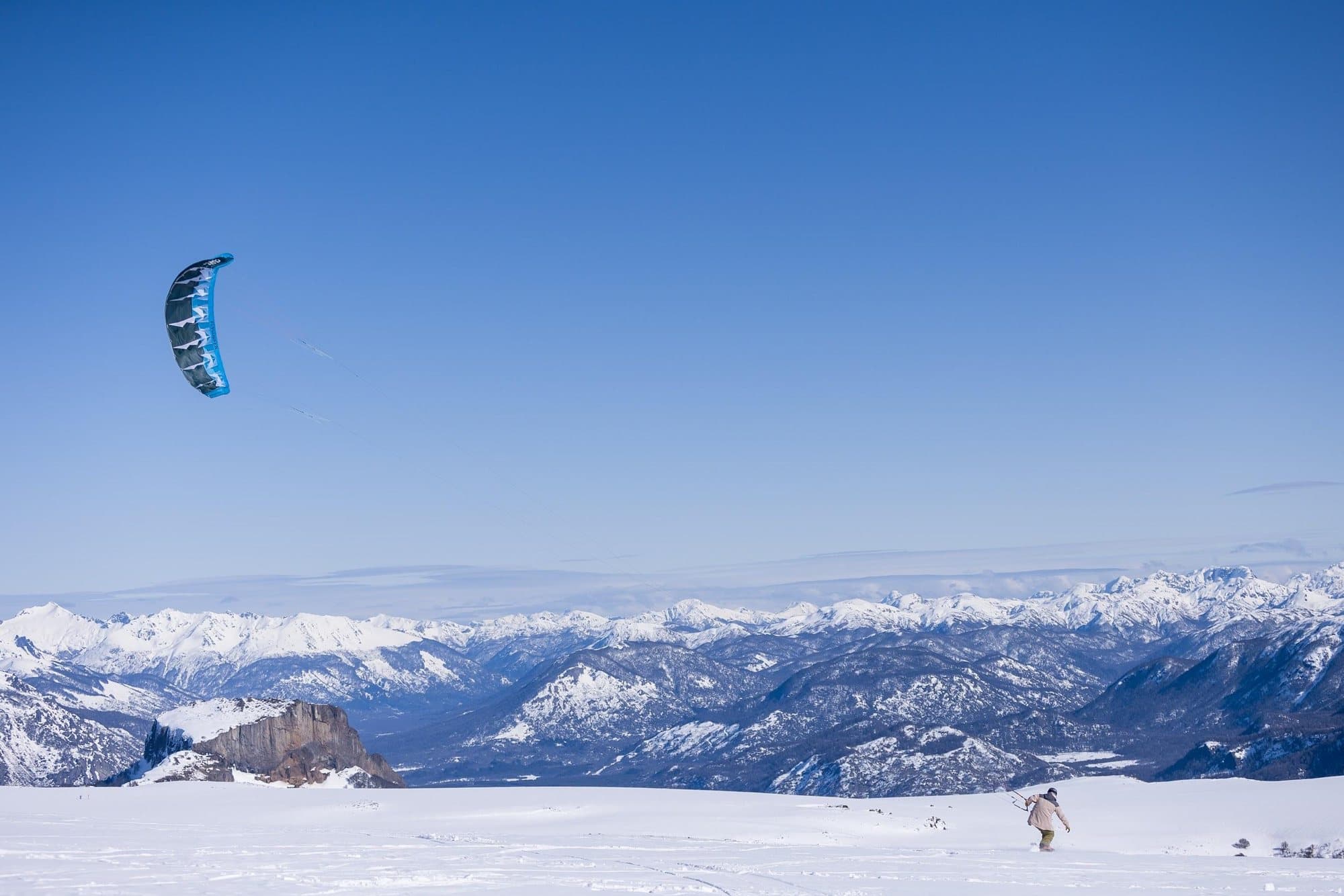 A snowkiter crossing the Chapelco highlands with the Andes behind