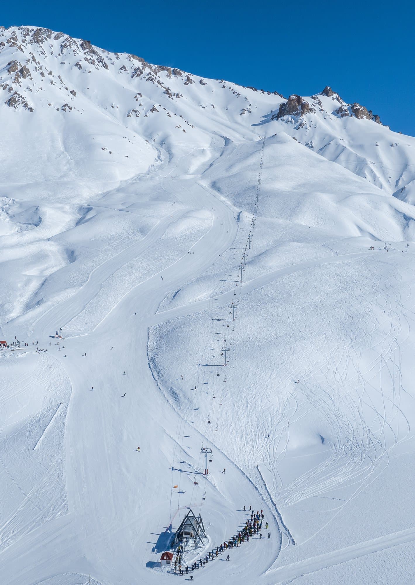 Aerial view of a Las Leñas chairlift climbing toward rocky Andean peaks