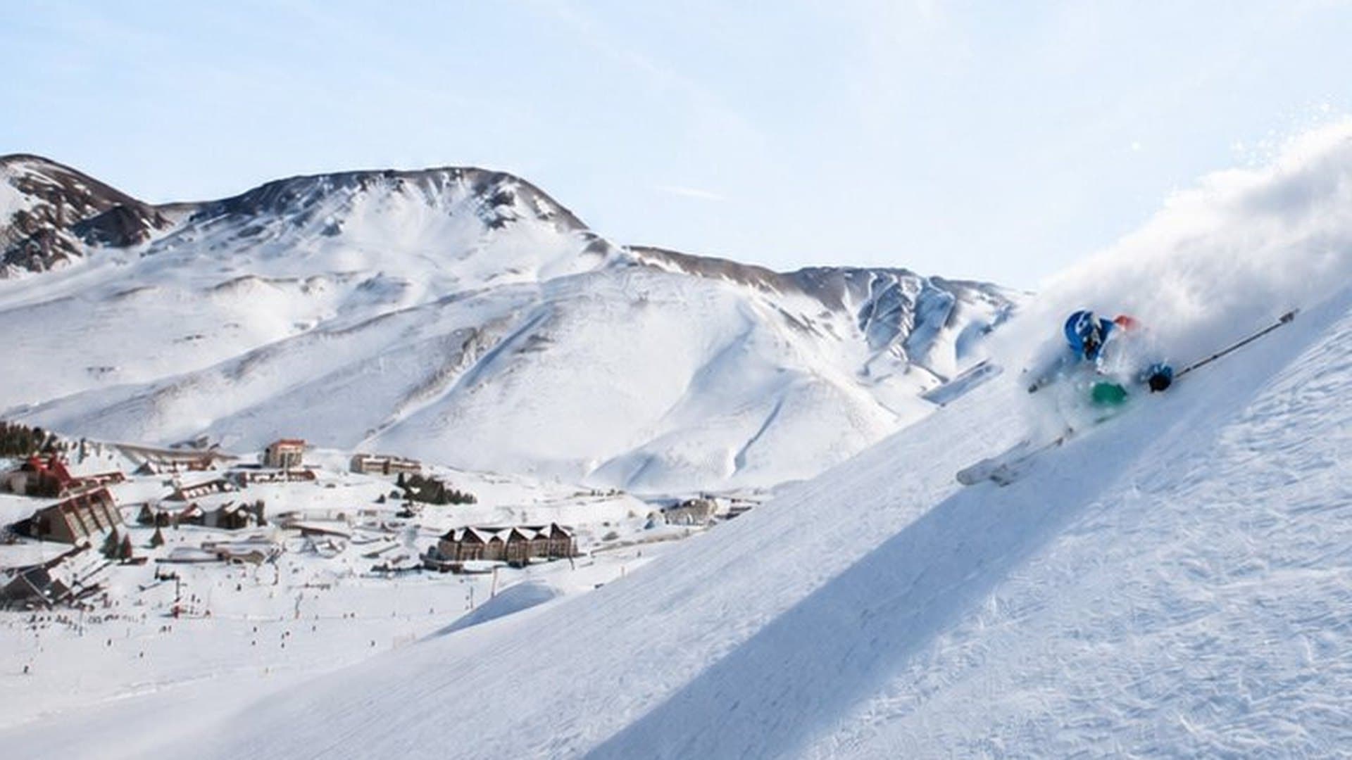 A skier carving fresh snow above the Las Leñas village
